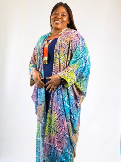 Woman wearing multicolor African batik kimono over navy blue outfit, smiling confidently
