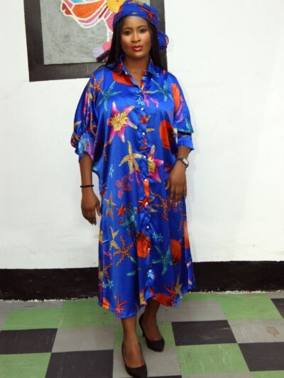 Woman wearing a blue satin kaftan dress with colorful ocean prints and matching headwrap